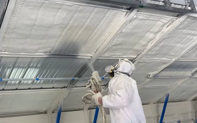 Spray foam applied to the underside of a commercial roof deck from a lift